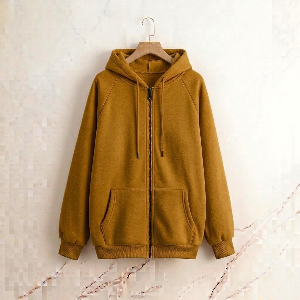 A mustard yellow full-zip hoodie with a drawstring hood and front pockets, hanging on a wooden hanger against a light beige marble-textured wall.