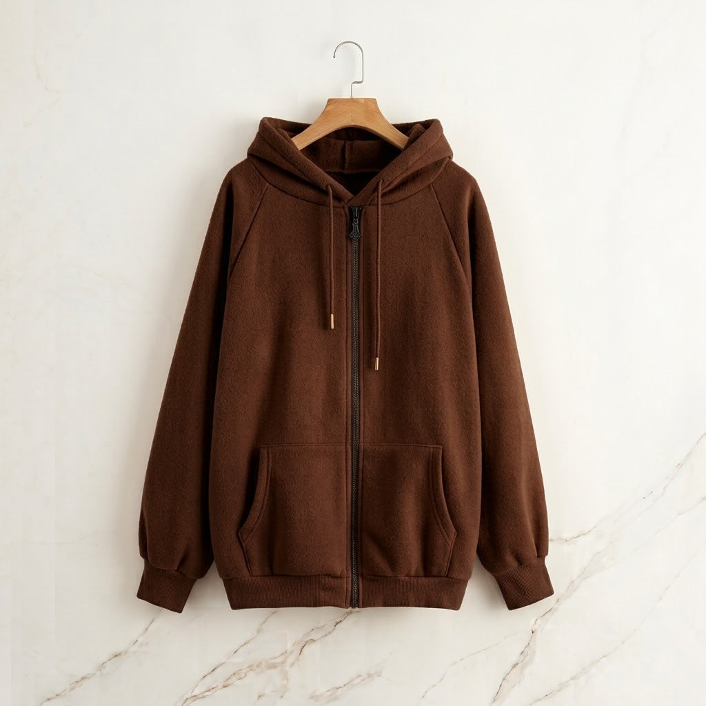 A brown zip-up hoodie with a drawstring hood and kangaroo pockets, hanging on a wooden hanger against a light marble-textured wall.