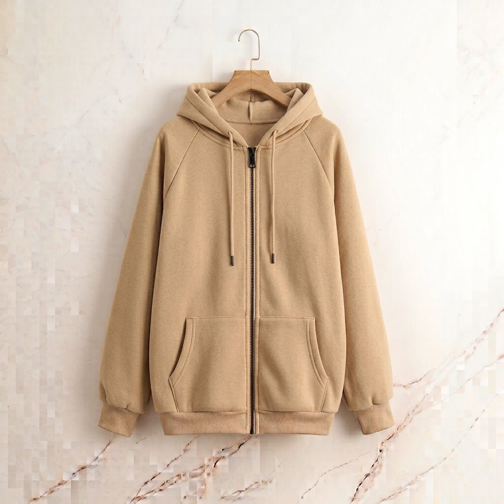 A beige zip-up hoodie with a drawstring hood and front pockets, hanging on a wooden hanger against a light marble-textured wall.
